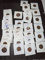 Lot of 38 1940s Wheat Pennies individually carded. Coins labeled with years and mint marks, placed flat on dark surface.