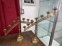 Pair of brass candelabras displayed side by side showing their adjustable arms and overall height.