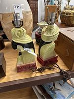 Side view of two ceramic bust lamps showing illumination hardware and ceramic detailing.