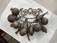 Overall view of the vintage brass Penca De Balangandan door chime with hanging fruit-shaped charms displayed on white background.