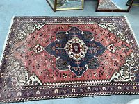 Full view of Persian wool rug with central medallion and border pattern, showing overall design and condition.