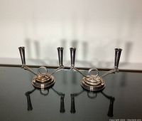 Two identical candlestick holders on reflective surface