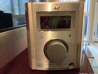 Front view of JVC FS-7000 central control unit with display screen and large volume knob visible.