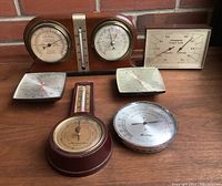 Set of six vintage climate instruments in a group showing variety of dials, brands include Presto, Ideal, Airguide, Brooklyn, with wood and metal cases.