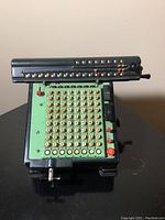 Front view of the Monroe high speed adding calculator showing the numeric keys, plus and minus buttons, and the mechanical number display on top.
