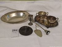 Eight items displayed on white background: oval bowl, sugar and creamer on tray, etched cat plate, candle snuffer, leaf tray, Mexican sombrero dish, etched cup