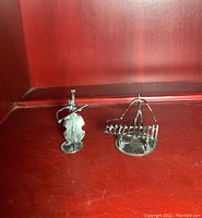 Two sterling silver miniature sculptures of musicians playing bass and xylophone on a wooden surface, showing size and details.