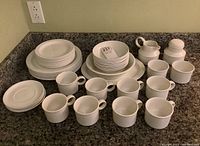 Full set arranged on countertop showing plates, bowls, mugs, creamer and sugar bowl