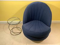 Swivel chair next to side table against yellow wall and carpeted floor