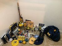 Wide shot of multiple University of Michigan fan items including hats, glasses, memorabilia, and accessories