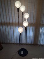 Front view of lamp with all five globes illuminated against window blinds
