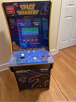 Front view of cabinet powered on showing marquee, screen displaying gameplay, control panel