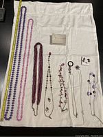 All eight necklaces and three pairs of earrings laid out on white cloth for overview