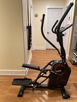 Side view of the elliptical machine showing foot pedals and frame.