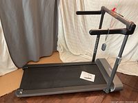 Front view of treadmill unfolded showing running belt and handrails
