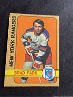 Front view of Brad Park hockey card showing player in New York Rangers uniform with orange background and text.