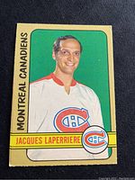 Front of 1972-73 O-Pee-Chee Jacques Laperriere hockey card showing player in Montreal Canadiens jersey on green background with team name and player name.