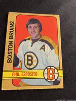 Front side of the 1972-73 Phil Esposito hockey card showing his portrait in Boston Bruins jersey with team name and player name in yellow bar.