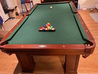 Front view of pool table with racked balls and cue ball on green felt