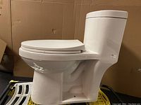 Side view of the white one piece dual flush toilet showing elongated oval seat and integrated tank and bowl design