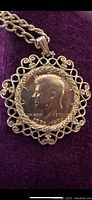 Front view of the Kennedy half dollar coin embedded in decorative metal pendant frame with chain on dark background.