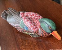 Top angle showing colorful hand painted feathers, green head, and orange beak on wooden duck figurine.