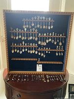 Front view of the handcrafted wooden spoon display case with multiple rows holding collector spoons.