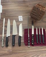 Complete set of 8 cutting utensils, sharpener, and wooden block displayed on wood floor.