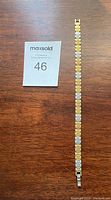 Full length view of the front side of the two-tone stainless steel magnetic bracelet showing alternating gold and silver links.