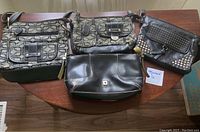 Four purses displayed on table showing front sides and overall condition.
