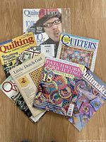 Seven quilting magazines arranged on floor with visible titles and colorful quilt-themed covers