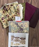 Assorted fabrics including large floral fabric, solid complementary fabrics, and folded floral fabric pieces on floor
