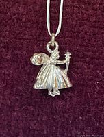 Close-up photo of the sterling silver fairy charm pendant on a cloth background, showing detailed figure of fairy with wings, holding a wand.
