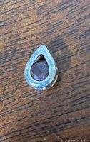 Close-up of the front of the sterling silver teardrop pendant with amethyst stone set in the center, showing stamped 925 and gemstone details.