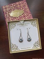 Front view of earrings in gift box showing teardrop shape design and blue topaz stones