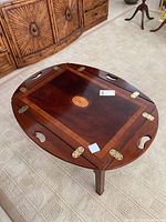 Wooden butler's table folded down showing central inset and brass hinges.