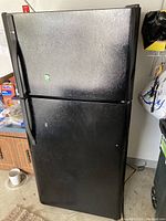 Full front view of the black Kenmore refrigerator with top freezer compartment, showing the textured black finish and vertical handles.