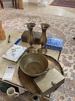 Overview of metal ware items on table including platter, bowl, vases, matchbox holder, storage box, Wedgwood card case, and poker cards.