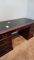Full view of the dark wood office desk showing leather insert tabletop and column of drawers on each side.