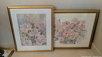 Two framed original watercolor floral prints leaning against wall, shown together.