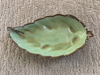 Top-down photo of green glazed leaf-shaped Frankoma pottery dish with brown edges and leaf details.