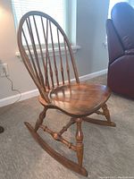 Right-side angle view of the child's wooden Windsor rocking chair showing spindle back, contoured seat, and turned legs on rockers.