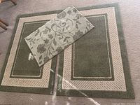 Photo showing two larger rubber back area rugs with sage green center and beige borders laid side by side, with the smaller floral patterned rug placed on top