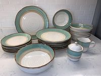 Full set showing dinner plates, luncheon plates, bowls, creamer, sugar with lid and serving bowl arranged on countertop.