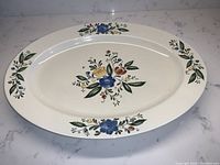 Full view of the oval ceramic platter with floral folk art decorations on rim and center.