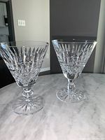 Pair of clear Waterford Tramore crystal claret glasses on marble surface showing full glasses and pattern details.