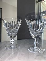 Pair of Waterford Tramore claret wine glasses on a grey marble surface with a background of a window and wall.