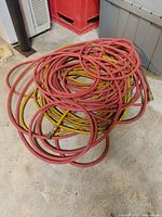 Coiled red and yellow air hoses on floor with metal fittings on ends