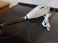 Full view of the handheld vacuum cleaner with attached nozzle tip on a stovetop surface.