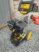Front and side view of Champion 3000 PSI gas power washer showing engine, control panel with PSI and spray degree info, and large yellow wheels standing on gravel.